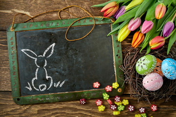 Eastern bunny on blackboard decorated with tulips