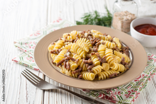 Plakat Fusilli makaron z mielonym mięsem i cebulą w stylu marynarskim na biały drewniany stół. Makarony po flotski, danie rosyjskie.