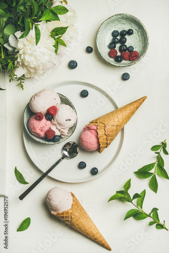 Plakat Flat-lay z Pink truskawek i kokosowe lody łopaty w misce, słodkie gofry, bukiet kwiaty piwonii i świeże jagody na białym tle, widok z góry. Koncepcja letniej żywności