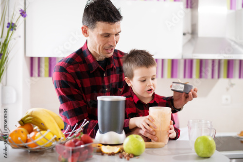 Fotoobraz na płótnie Ojciec i syn w tej samej koszuli, otwierając misę blendera po tym, jak robi się mieszanie ich smoothy.