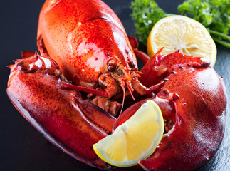 Red lobster with lemon and green on black wooden background