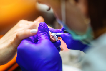 Woman hands in a nail salon receiving a manicure. Close up, selective focus.