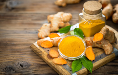 Turmeric powder and turmeric roots on the wooden table