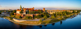 Krakow, Poland. Wide aerial panorama at sunset with Royal Wawel castle and cathedral. Far view of old city and old Jewish Kazimierz district. Vistula river bank, park, promenade and walking people