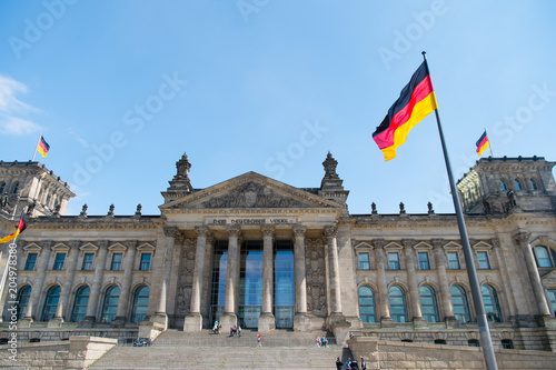 Zdjęcie XXL Niemieckie flagi na wietrze w słynnym budynku Reichstagu, siedziba niemieckiego parlamentu (Deutscher Bundestag), w słoneczny dzień z błękitne niebo i chmury, centralny berliński dzielnicy Mitte, Niemcy