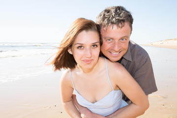 Couple cuddling affectionate on the beach in summer with the sea in background