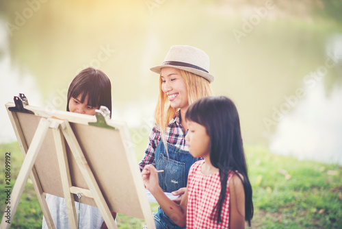 Фото: Mother and daughter drawing picture together in the park Mother and daughter drawing picture together in the park