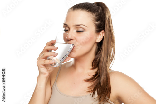 Фото: happy woman drinks water from a glass on white background happy woman drinks water from a glass on white background