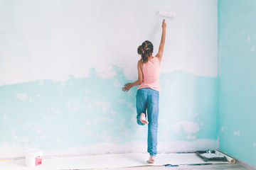 Child painting a wall in room