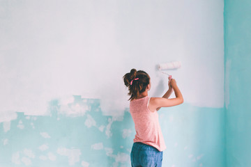 Child painting a wall in room
