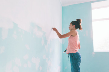 Child painting a wall in room