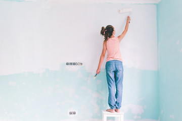 Child painting a wall in room