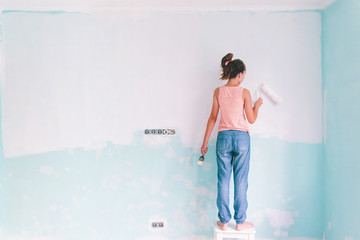 Child painting a wall in room