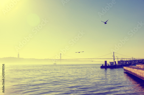 Zdjęcie XXL Widok most nad Tagus rzeką, Lisbon, Portugalia. Mewy krążą nad wodą w słońcu, pięknym mieście i naturalnym krajobrazie