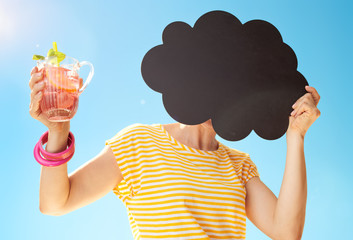 woman with refreshing cocktail hiding behind cloud shaped blackboard