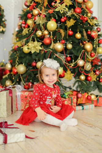 Фото: Young mother wearing white dress and keeping little female baby near Christmas tree. Concept of New Yea decoration and happy parent. Young mother wearing white dress and keeping little female baby near Christmas tree. Concept of New Yea decoration and happy parent.