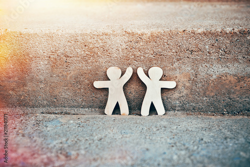 Фото: Wooden little men holding hands on natural stone background. Symbol of friendship, love and teamwork Wooden little men holding hands on natural stone background. Symbol of friendship, love and teamwork