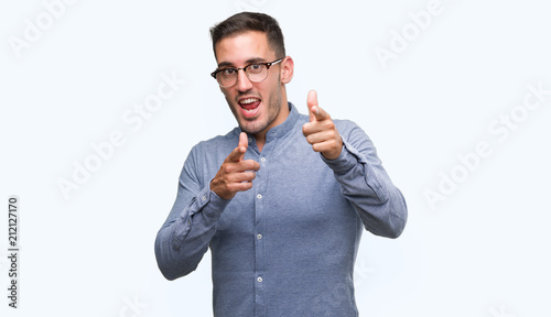 Фото: Handsome young elegant man wearing glasses pointing fingers to camera with happy and funny face. Good energy and vibes. Handsome young elegant man wearing glasses pointing fingers to camera with happy and funny face. Good energy and vibes.