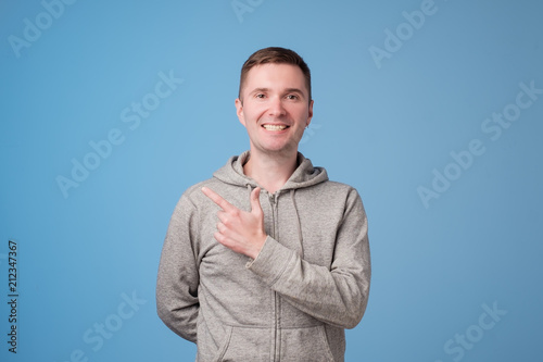 Фото: Cheerful handsome man showing direction and pointing with finger Cheerful handsome man showing direction and pointing with finger
