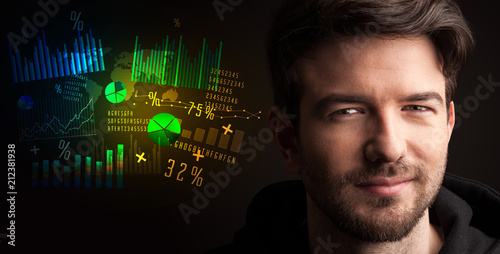 Фото: Portrait of a young businessman with colorful charts and graphs next to him on a dark background Portrait of a young businessman with colorful charts and graphs next to him on a dark background