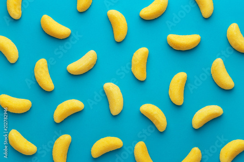 Фото: Banana shaped candy pattern on a blue background. Jelly candies viewed from above. Top view. Repetition concept Banana shaped candy pattern on a blue background. Jelly candies viewed from above. Top view. Repetition concept