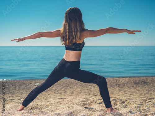 Woman in warrior yoga pose on beach Woman in warrior yoga pose on beach