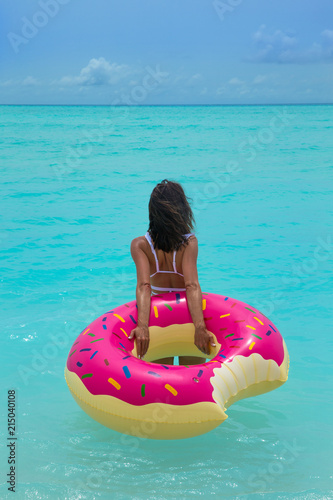 Woman with inflatable donut on the beach in summer sunny day. Summer vacation concept. Woman with inflatable donut on the beach in summer sunny day. Summer vacation concept.