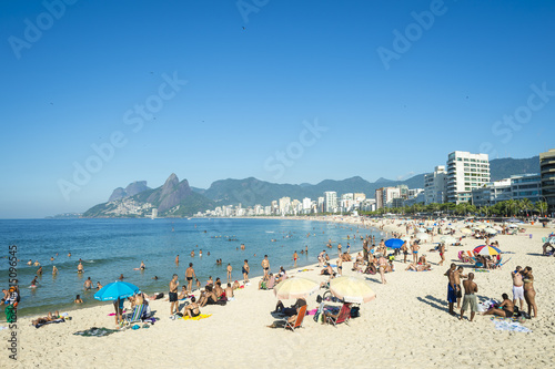 Rio residents, known as cariocas, relax at the Arpoador section of Ipanema Beach with the city skyline and Two Brothers Mountain in the background. Rio residents, known as cariocas, relax at the Arpoador section of Ipanema Beach with the city skyline and Two Brothers Mountain in the background.