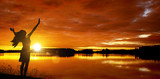 Frau bei Sonnenaufgang am See
