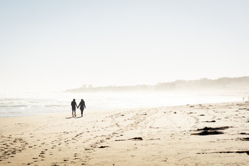 Pareja de enamorados caminando por la playa tomados de las manos 