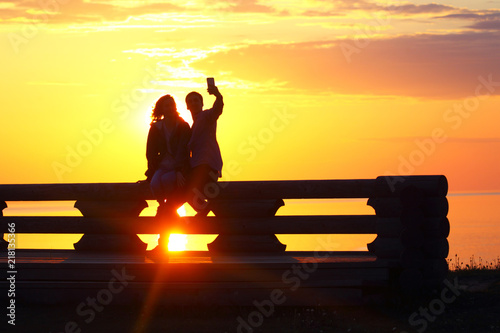 Foto obraz na płótnie canvas jednoczęściowy - Silhouette young couple at sunset by the sea. Selfie