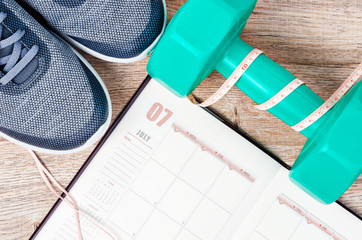 Calendar plan with green dumbbell and sneakers.