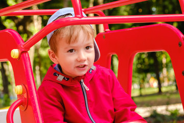 Boy playing on playground carousel in the park