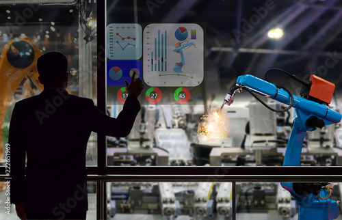 Zdjęcie XXL Ekran dotykowy inżyniera kontroluje produkcję fabrycznych robotów przemysłowych i ramię mechaniczne