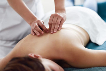 Young woman receiving a back massage by professional therapist.