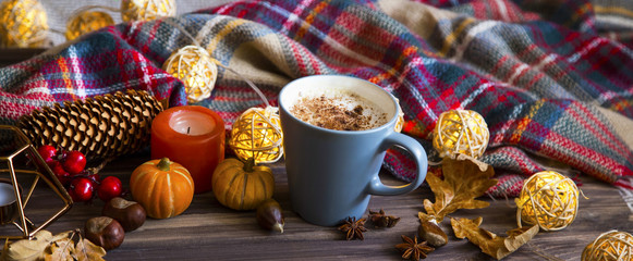 Cup of coffee with autumn decorations and cozy scarf