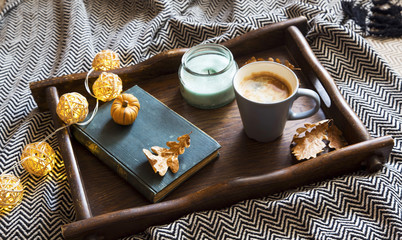Fall cosy setting with wooden tray, blanket and cup of coffee