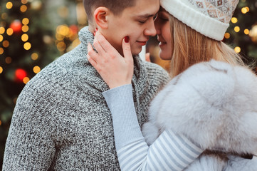 happy loving couple kisses, enjoying Christmas or New year Holidays outdoor, walking on city streets decorated with lights