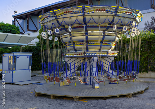 Zdjęcie XXL Empty Carousel Merry-Go-Round z miejscami zawieszonymi na łańcuchach bez ludzi czekających na swoich gości. Letni wieczór w miejskim parku rozrywki.