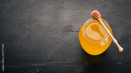 Honey in a jar on a black wooden background. Free space for text. Top view. © Yaruniv-Studio