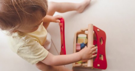 Cute little baby boy playing with small wooden house close up top view