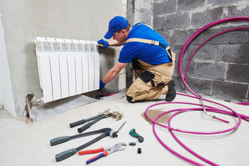 plumber at work. Installing water heating radiator