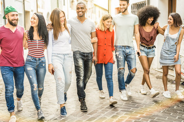 Multiracial millennial friends walking and talking in city center - Happy guys and girls having fun around old town streets - University students on travel vacations  - Warm shadow filter tone
