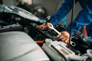 Male technician works with car engine