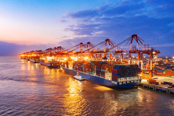 Container ship in export and import business and logistics. Shipping cargo to harbor by crane. Water transport International. Aerial view