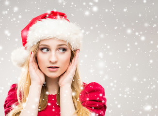 Attractive and beautiful girl in Christmas hat over winter background with snowflakes.