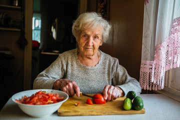 Elderly woman prepares a meal in a village house.