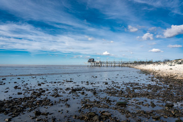 bord de mer en Vendée avec des galets et une maison sur pilotis au loin