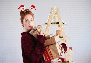 Shocked girl holding stack of christmas present