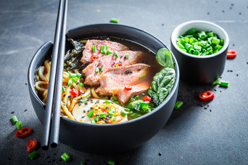 Ramen soup with noodles and spinach on concrete table